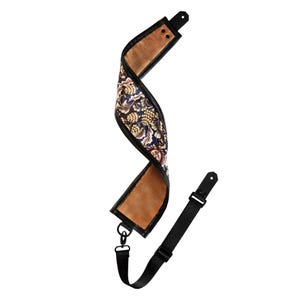 Peut inclure: Une sangle de guitare avec un motif floral dans les tons marron, bleu et or. La sangle a une bordure en cuir noir et une sangle en nylon noir réglable avec un clip en métal.