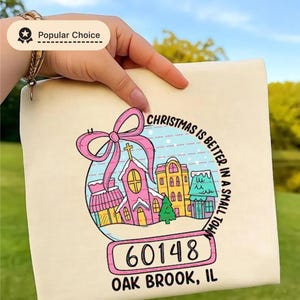 Camiseta "O Natal é Melhor em uma Cidade Pequena", Camiseta Personalizada com o Nome da Cidade e CEP, Camiseta Fofa com Vila Natalina em Tons Pastel, Presente de Natal Personalizado