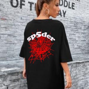 Puede incluir: Camiseta negra de gran tamaño con un gráfico de telaraña roja y el texto "sp5der" en letras blancas.