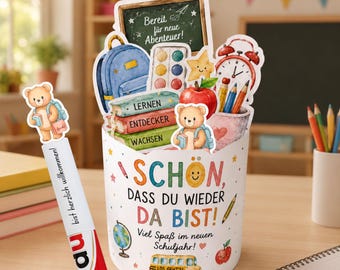 Könnte beinhalten: Ein zylindrischer Behälter mit schulbezogenen Illustrationen, darunter eine Tafel mit Text, ein blauer Rucksack, Bücher mit der Aufschrift Lernen, Entdecker, Wachsen und ein roter Wecker. Vorne steht der Text SCHON, DASS DU WIEDER DA BIST!