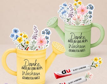 Könnte beinhalten: Eine gelbe Gießkanne und eine hellgrüne Gießkanne, jeweils gefüllt mit bunten Blumen-Ausschnitten. Die gelbe Kanne trägt den Text "Danke, dass du mir beim Wachsen geholfen hast" und die grüne "Danke, dass du uns beim Wachsen geholfen hast". Zwei Schokoriegel mit der Aufschrift "du bist wunderbar" liegen dabei.