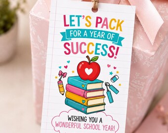 Può includere: Un'etichetta regalo rettangolare bianca con foro e spago, che riporta il testo LET'S PACK FOR A YEAR OF SUCCESS! WISHING YOU A WONDERFUL SCHOOL YEAR! FROM: Olivia. Il design include una pila di libri colorati, una mela rossa e un righello.
