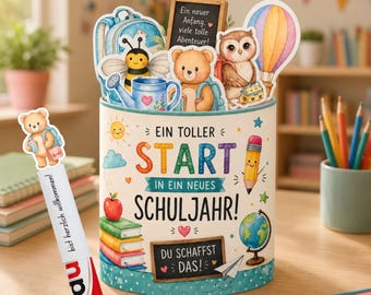 Könnte beinhalten: Ein zylindrischer Behälter mit cremefarbenem Hintergrund und bunten Illustrationen von Biene, Bär, Eule, Heißluftballon, Büchern und Globus. Der Text lautet: EIN TOLLER START IN EIN NEUES SCHULJAHR! DU SCHAFFST DAS! Inklusive passendem Lesezeichen.