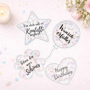 May include: Four decorative stickers in star, balloon, clover, and heart shapes. Each sticker has a clear border and is filled with confetti. Text includes "Für dich soll es Konfetti regnen!", "Wunscherfüller", "Gönn dir was Schönes", and "Happy Birthday".