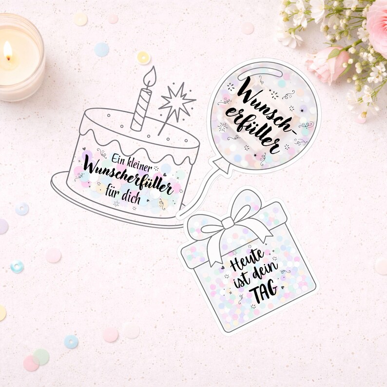 Pu&ograve; includere: Illustrazione a tema compleanno con torta, palloncino e confezione regalo. La torta ha il testo "Ein kleiner Wunscherf&uuml;ller f&uuml;r dich." Il palloncino dice "Wunscherf&uuml;ller", e la confezione regalo dice "Heute ist dein TAG."