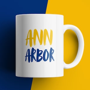 Ann Arbor coffee mug blue and yellow brush text ceramic Michigan city pride gift college town souvenir for fans alumni students decor