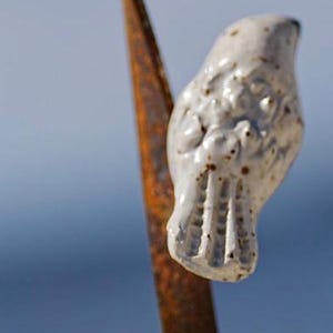 Keramische Vögel thront auf einem Gartenstecker mit Grashalm aus Metall.