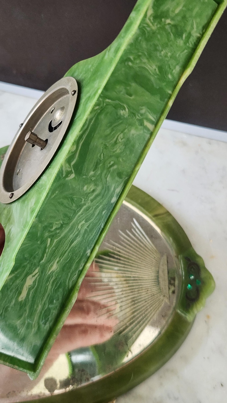 May include: Vintage green and white marbled vanity tray with a silver-toned metal accent. The tray has a decorative shape with a matching hand mirror. The mirror has a silver-toned metal back and a decorative design.