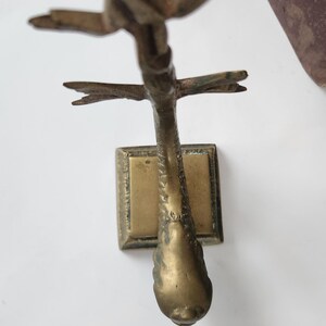May include: A vintage brass sculpture of a bird in flight. The sculpture has a rectangular base and a detailed bird form with outstretched wings. The brass has a warm, aged patina, suggesting its antique nature. The bird's form is detailed and elegant.