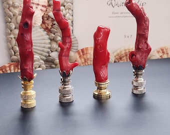 May include: Four red coral lamp finials with gold and silver bases. The finials are displayed on a black surface.