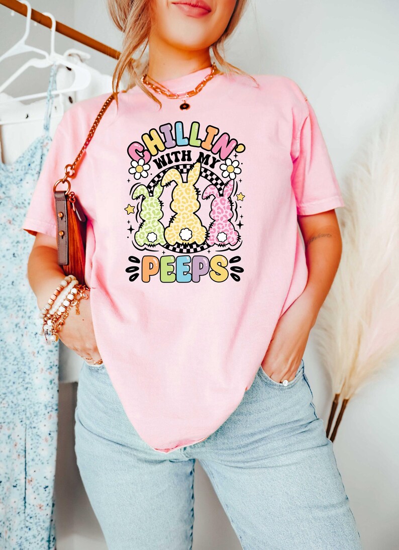 May include: Pink t-shirt with a graphic of three pastel colored bunnies with the text "Chillin' with my peeps" in rainbow colors.