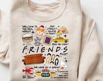 Op de afbeelding: Beige Friends-thema sweatshirt met diverse grafische elementen. Voorzien van het logo van de show en iconische beelden zoals een kalkoen met zonnebril, een gele taxi en het Central Perk-logo. Tekst bevat zinnen uit de show.