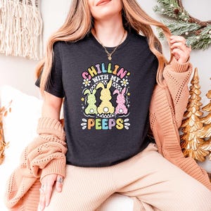 May include: A black t-shirt with a graphic of three pastel-colored Peeps chicks and the text "Chillin' with my Peeps".
