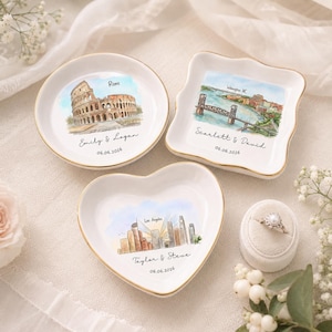 May include: Three white ceramic trinket dishes with gold-painted rims. One round dish features the Colosseum and text "Rome Emily & Logan 06.06.2026". One square dish shows a bridge and "Wilmington NC Scarlett & David 06.06.2026". One heart dish shows "Los Angeles Taylor & Steve 06.06.2026".