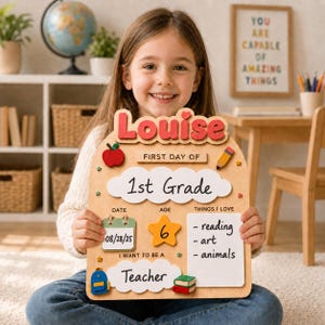May include: A wooden first day of school sign featuring the name Louise in red letters, a cloud shape with 1st Grade, a calendar showing 08/28/25, a yellow star with the number 6, and a white board listing reading, art, and animals as interests.