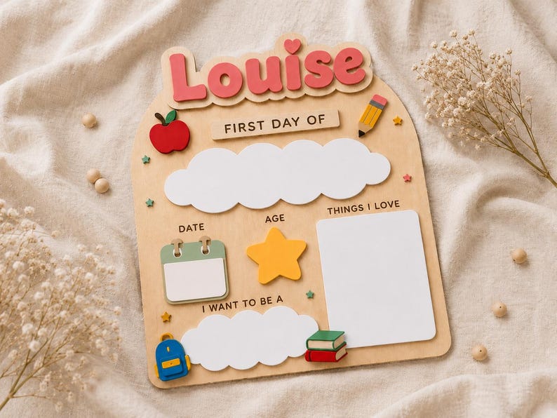 May include: A wooden arch-shaped sign with the name Louise in pink letters at the top. It features the text FIRST DAY OF, DATE, AGE, THINGS I LOVE, and I WANT TO BE A. Includes cutouts of an apple, pencil, calendar, star, backpack, and books.