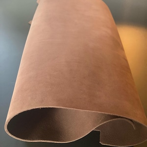 May include: A piece of brown leather, folded in half, showing the smooth, soft texture of the material.