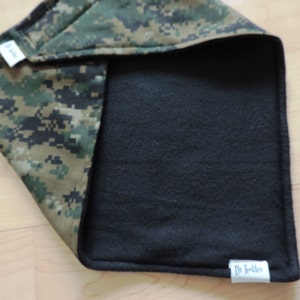 May include: A reversible baby blanket with a digital camouflage pattern on one side and black fleece on the other. The blanket has a tag that says "Dr. Toddler".