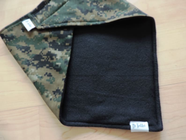 May include: A reversible baby blanket with a digital camouflage pattern on one side and black fleece on the other. The blanket has a tag that says "Dr. Toddler".
