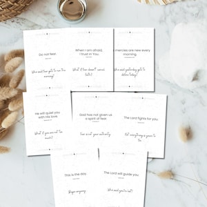May include: A collection of white cards with inspirational quotes in black text. The cards feature phrases like "Do not fear" and "When I am afraid, I trust in You." The cards are arranged on a marble surface.