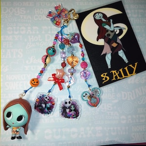 May include: A charm featuring a Sally figurine, colorful beads, and character pendants. A card with a Sally illustration and the name "SALLY" is also present. The charm includes a pumpkin, star, and heart.