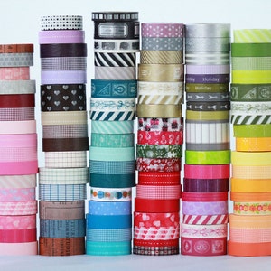 May include: A collection of colorful washi tapes stacked in columns. The tapes feature various patterns, including polka dots, stripes, hearts, and geometric designs.