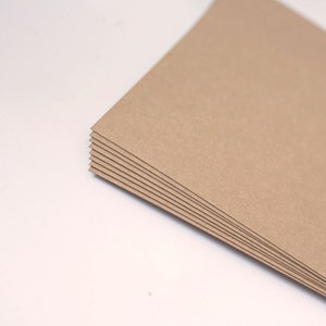 May include: A stack of brown cardboard sheets, likely for crafting or scrapbooking.