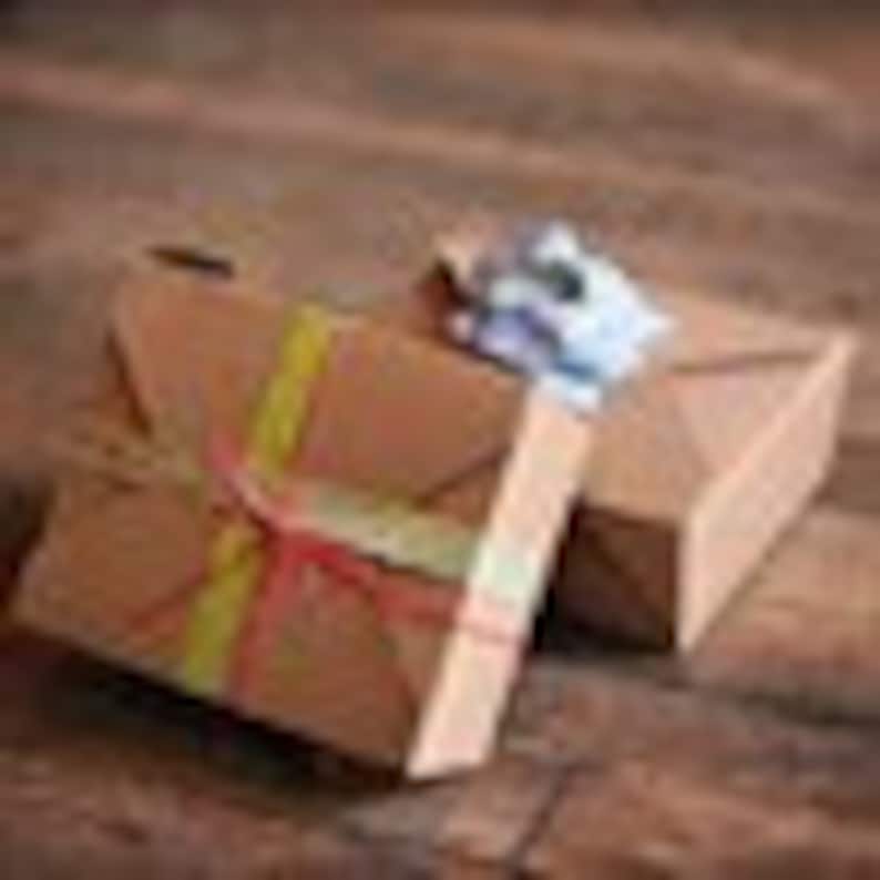 May include: Two brown cardboard gift boxes tied with twine and a yellow ribbon. The top box is open and the contents are visible.