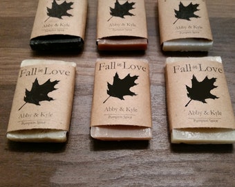 Puede incluir: Seis barras de jabón envueltas en papel marrón con una hoja de arce negra y el texto "Fall in Love" y "Abby & Kyle Pumpkin Spice".