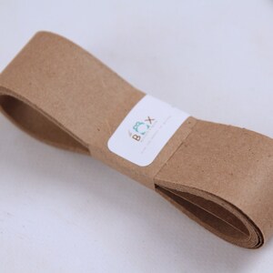 May include: A roll of brown paper tape with a white label that says "The Box" in blue and green lettering.