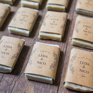 May include: A collection of small, rectangular bars of soap wrapped in brown paper with the text "LEDA & NICO" and the date "25 AUGUST 2017".