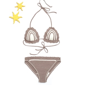 Op de afbeelding: Een bruine en witte gehaakte bikiniset. De top is een driehoekige stijl met verstelbare bandjes en strikjes aan de achterkant. De onderkant is een hoge snit met een gegolfde rand.