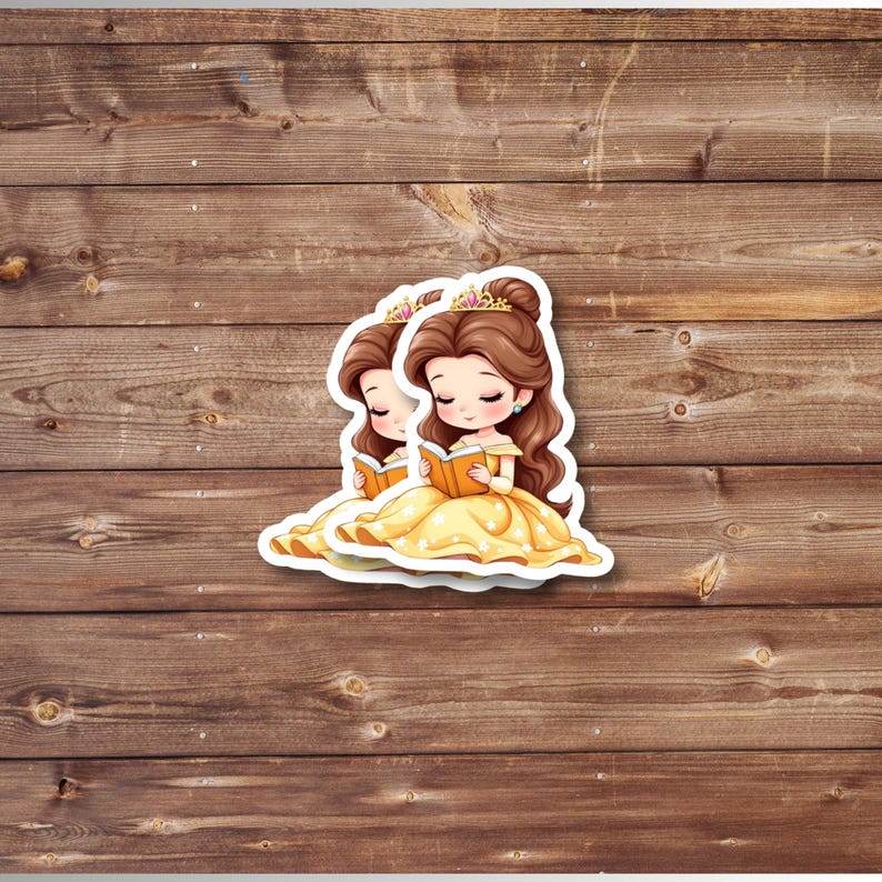 Puede incluir: Dos pegatinas con una ilustraci&oacute;n de dibujos animados de una princesa con un vestido amarillo, leyendo un libro. La princesa tiene el pelo casta&ntilde;o, una corona dorada y est&aacute; sentada. Las pegatinas est&aacute;n sobre un fondo de madera.