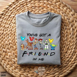 A gray t-shirt with a graphic design featuring characters from the animated film Toy Story, along with the text "You've got a friend in me" printed on it.