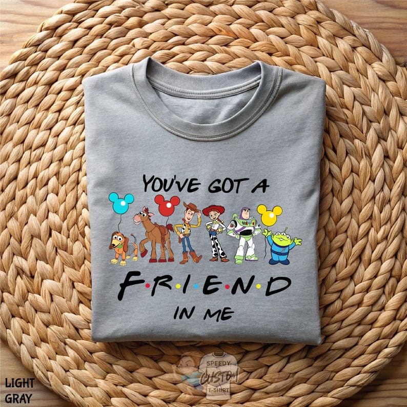 A gray t-shirt with a graphic design featuring characters from the animated film Toy Story, along with the text "You've got a friend in me" printed on it.