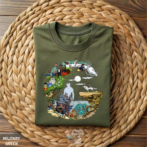 A green t-shirt with a colorful, illustrated design depicting various characters and scenes from the Studio Ghibli film "Ghibli's Castle".