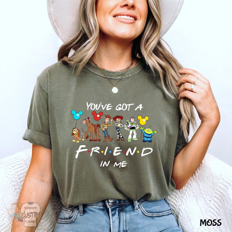 A woman wearing a green t-shirt with a graphic of characters from the TV show "Friend in Me" and the text "You've Got a FRIEND in ME" printed on it.