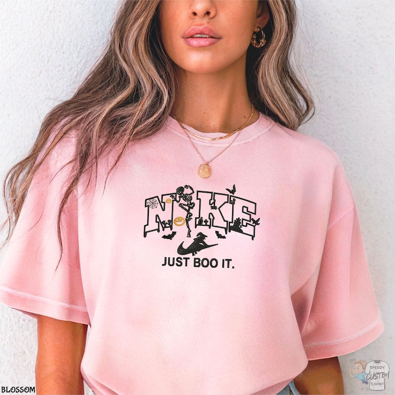 A woman wearing a pink t-shirt with a graphic design and text printed on it.