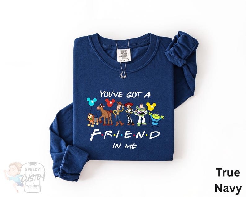 A navy blue long-sleeved t-shirt with a graphic design featuring characters from the TV show "Friends" and the text "You've Got a FRIEND in ME" printed on it.