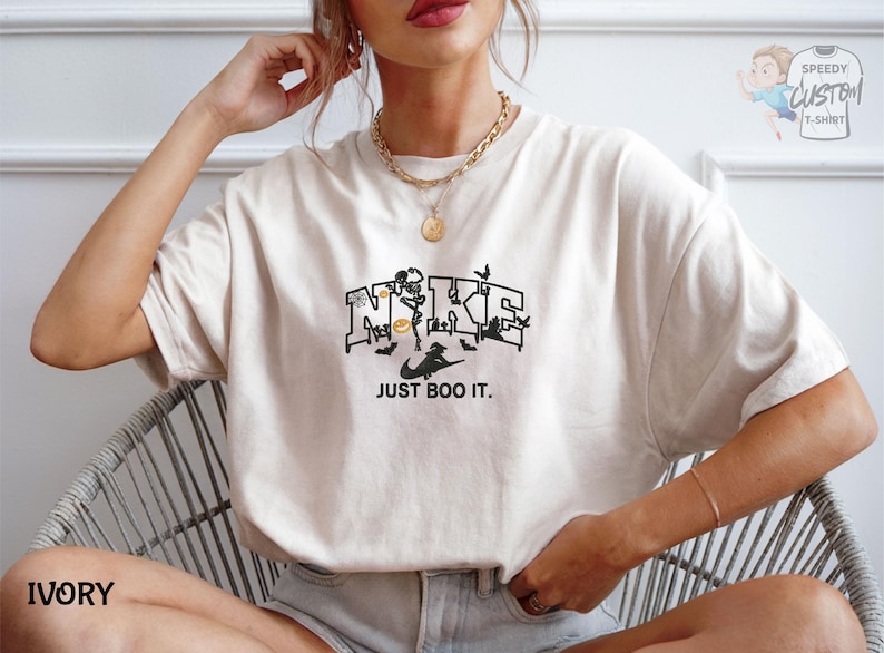 A woman wearing a white t-shirt with a graphic design and text, sitting in a chair.