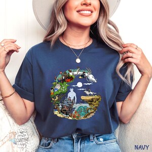 A woman wearing a navy blue t-shirt with a graphic design of a castle and a dragon, smiling and posing for the camera.