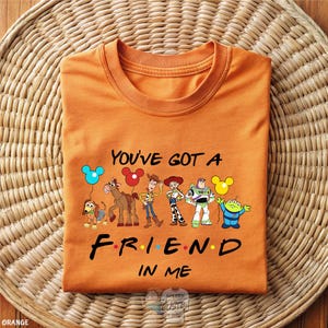 An orange t-shirt with a graphic design featuring characters from the TV show "Friends" and the text "You've Got a FRIEND in ME" printed on it.