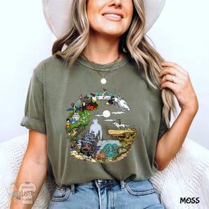 A woman wearing a green t-shirt with a colorful graphic design, smiling and posing for the camera.