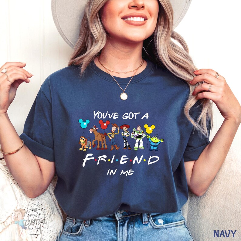A woman wearing a navy blue t-shirt with a graphic design of various Disney characters and the text "You've Got a FRIEND in ME" printed on it.
