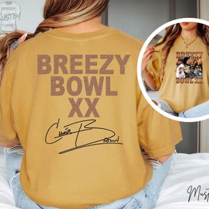 a person wearing a yellow t-shirt with the text "BREEZY BOWL XXX" printed on it.