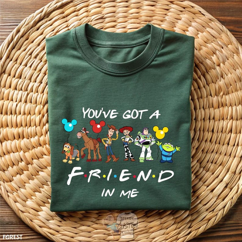 A green t-shirt with a graphic design featuring characters from the animated film Toy Story, along with the text "You've Got a Friend in Me" printed on it.