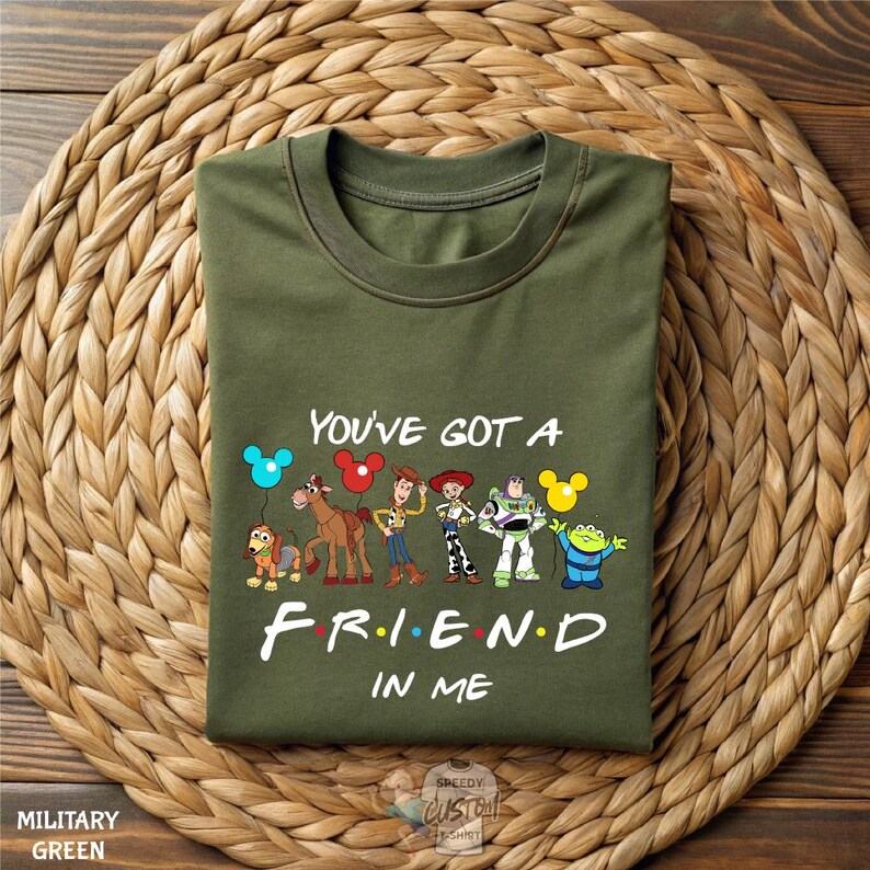 A green t-shirt with a printed design of characters from the TV show "Friends" and the text "You've got a FRIEND in me" printed on it.
