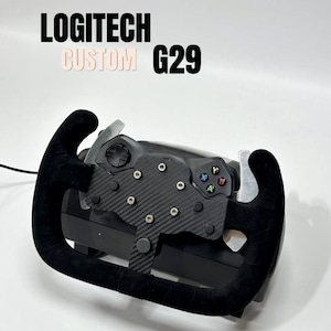 Pode incluir: Um volante de corrida Logitech G29 personalizado com um volante coberto de camurça preta e detalhes em fibra de carbono. O volante possui botões e borboletas de mudança. O texto "LOGITECH CUSTOM G29" é exibido no topo.
