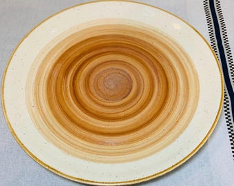 Puede incluir: Un plato de servir grande, redondo, de cerámica blanca con un diseño de espiral marrón. El plato tiene un borde ligeramente elevado.