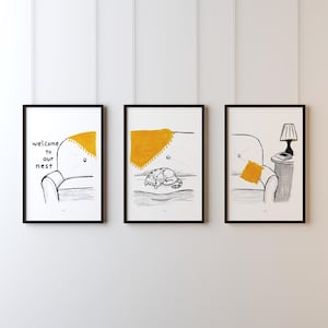May include: Three framed art prints with black frames. Each print features a black and white sketch of a couch with a yellow throw blanket and pillow. One print has the text "welcome to our nest".
